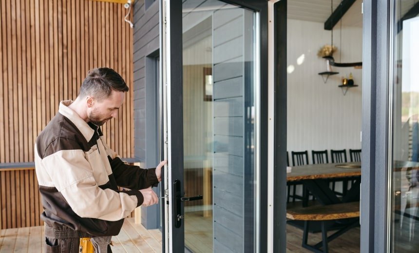 Trabajador instalando la cerradura de una puerta de vidrio.